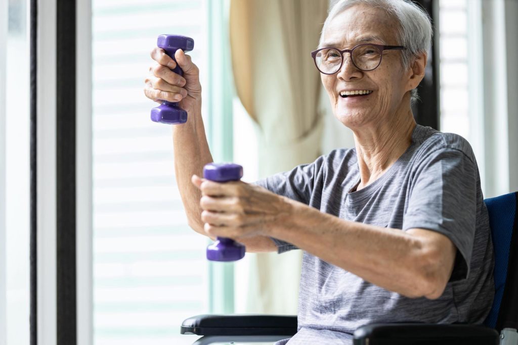 Strong asian senior woman working out with heavy dumbbells, lifting dumbbell weights for strength training.