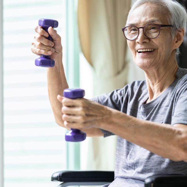 Strong asian senior woman working out with heavy dumbbells, lifting dumbbell weights for strength training.