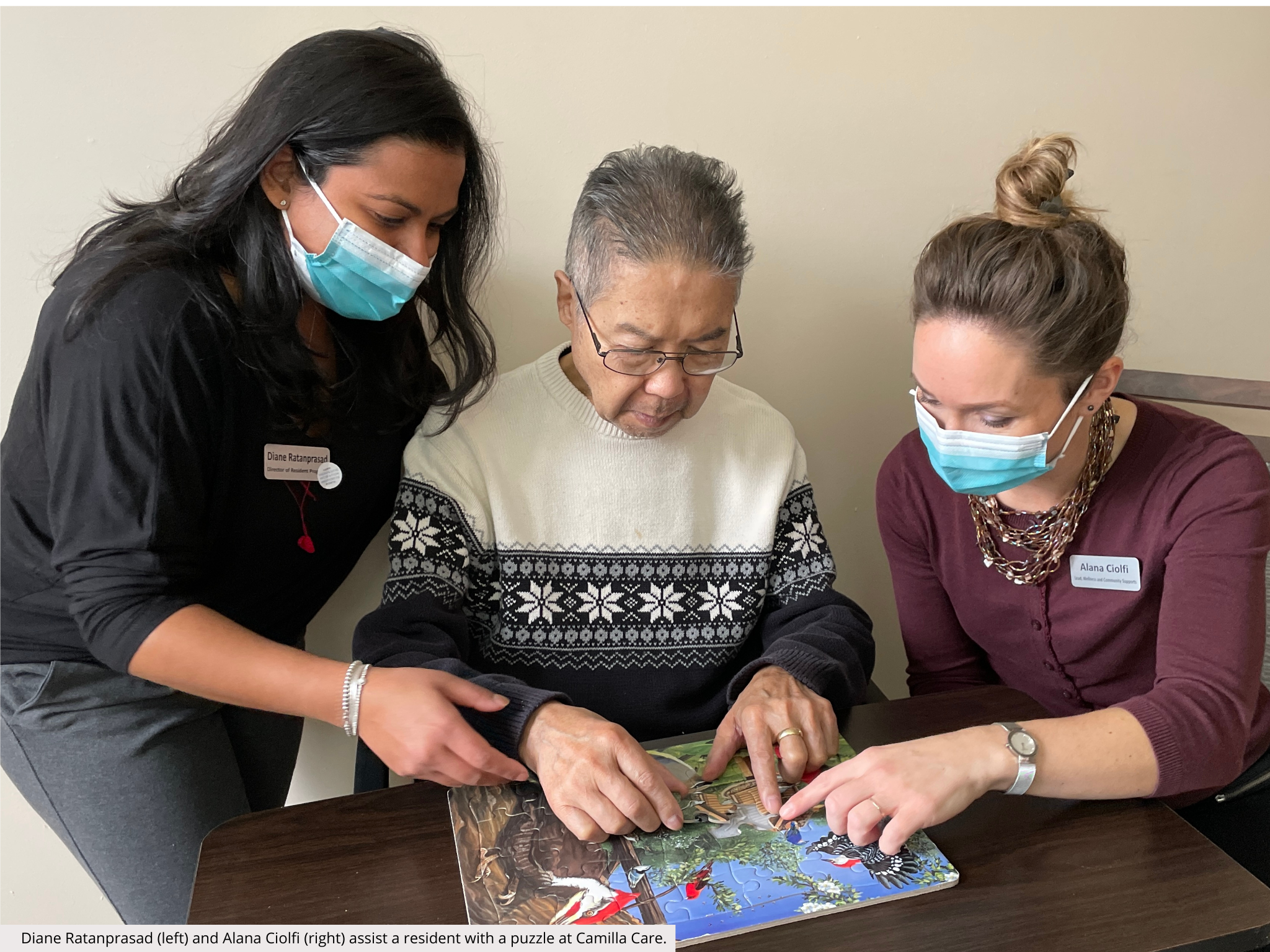 Diane Ratanprasad (left) and Alana Ciolfi (right) assist a resident with a puzzle at Camilla Care.